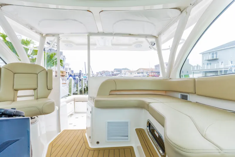 Slide: The Image of 2018 Pursuit OS 385 Offshore boat interior with beige seating and wood flooring. - 11