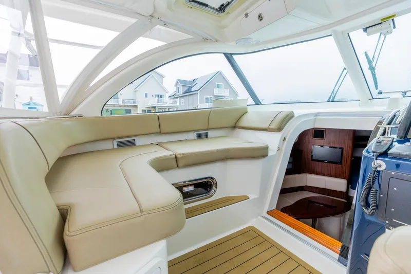 Slide: The Image of 2018 Pursuit OS 385 Offshore boat interior with beige seating and modern amenities. - 12