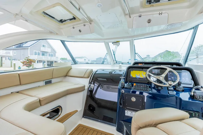 Slide: The Image of 2018 Pursuit OS 385 Offshore boat interior with modern helm and beige seating. - 13