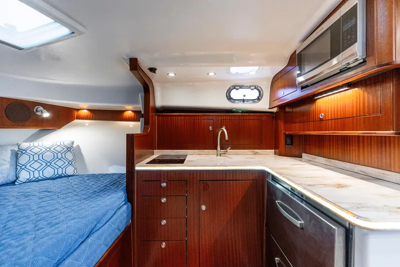 Slide: The Image of 2018 Pursuit OS 385 Offshore cabin interior with kitchenette, bed, and wooden cabinetry. - 17