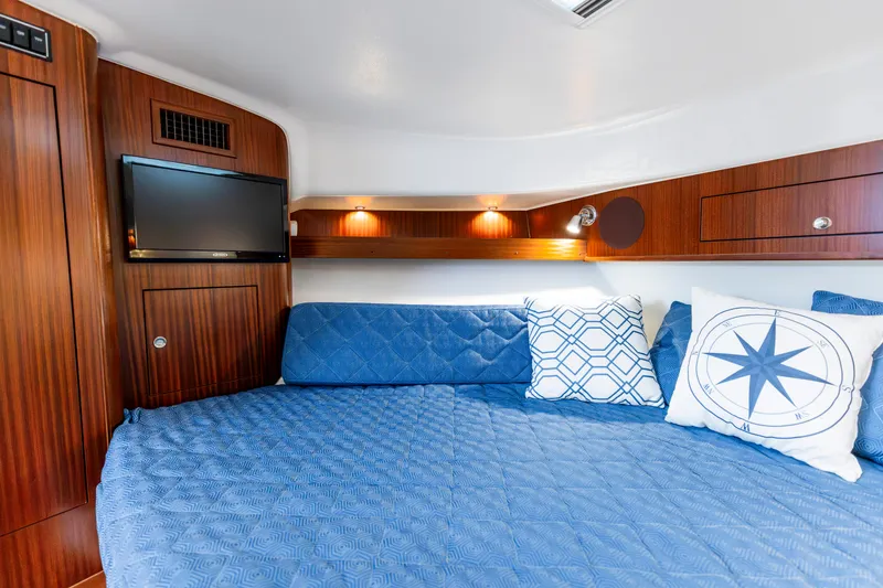 Slide: The Image of Luxurious cabin interior of 2018 Pursuit OS 385 Offshore with blue bedding and decorative pillows. - 18