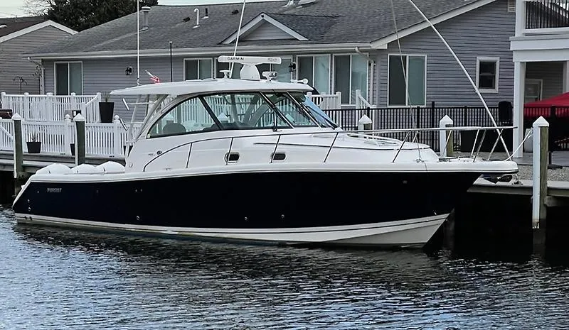 Slide: The Image of 2018 Pursuit OS 385 Offshore boat docked by waterfront homes. - 2