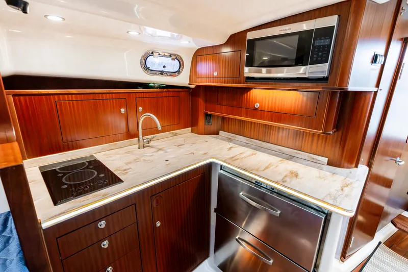 Slide: The Image of Luxurious 2018 Pursuit OS 385 Offshore yacht kitchen with wood cabinetry and modern appliances. - 20