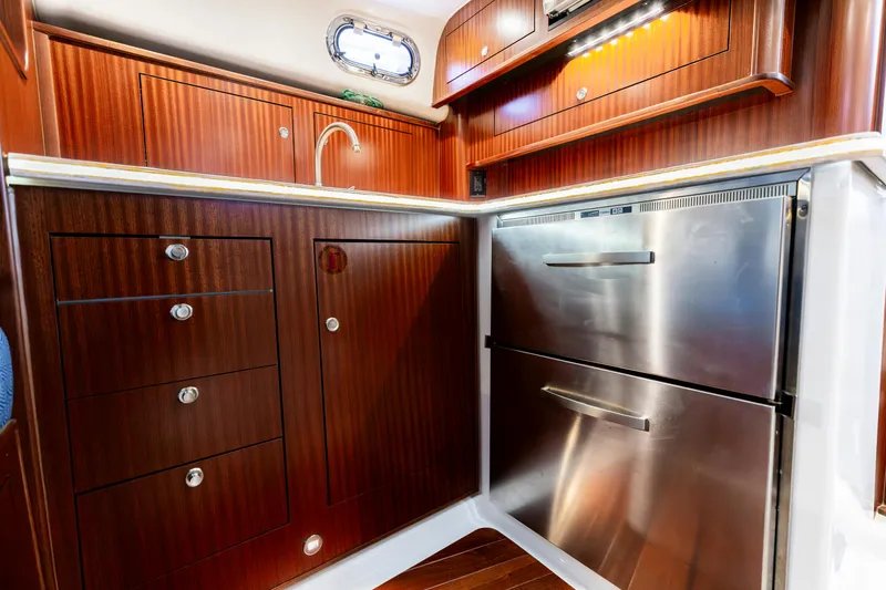 Slide: The Image of Luxurious 2018 Pursuit OS 385 Offshore yacht kitchen with wood cabinetry and stainless steel appliances. - 21