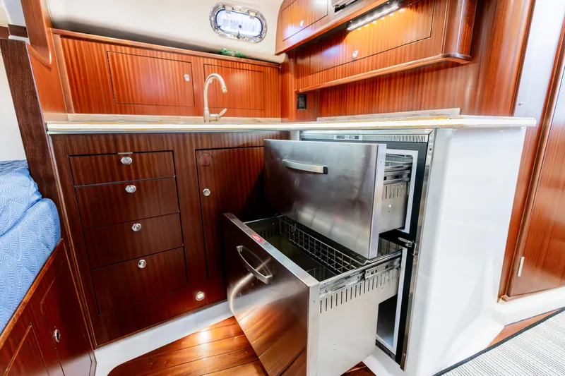 Slide: The Image of Luxurious 2018 Pursuit OS 385 Offshore yacht interior with wood cabinetry and stainless steel appliances. - 22