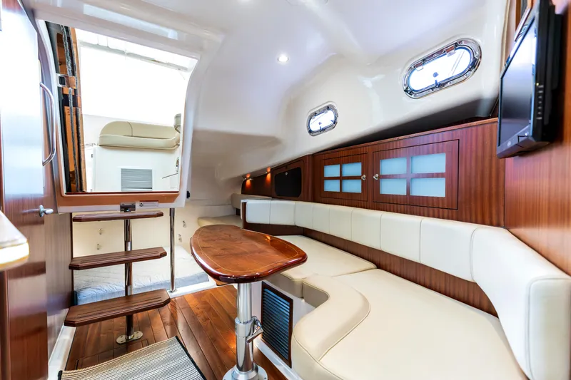 Slide: The Image of 2018 Pursuit OS 385 Offshore cabin interior with wooden accents and cream seating. - 23