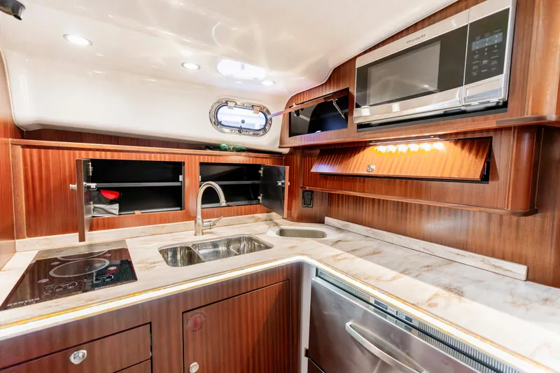 Slide: The Image of 2018 Pursuit OS 385 Offshore yacht kitchen with modern appliances and wood cabinetry. - 32
