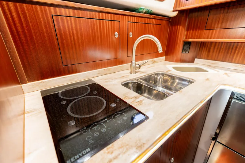 Slide: The Image of Luxurious 2018 Pursuit OS 385 Offshore yacht kitchen with stove, sink, and wooden cabinetry. - 33