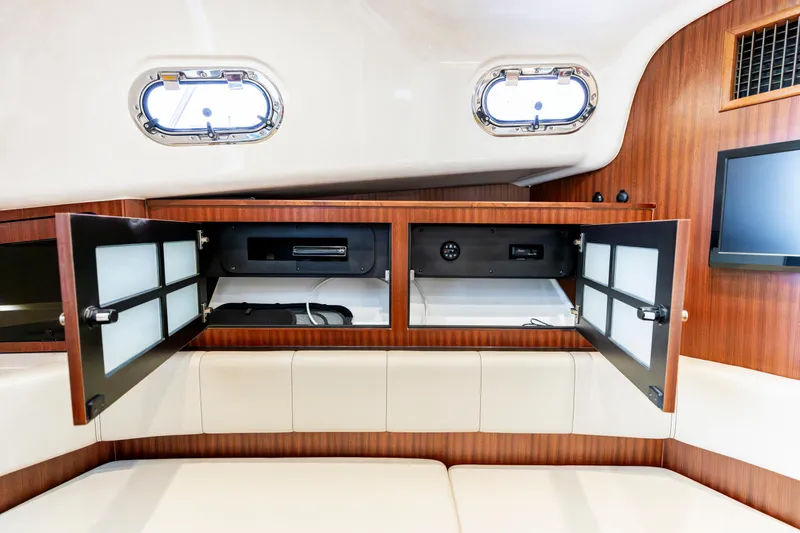 Slide: The Image of 2018 Pursuit OS 385 Offshore interior with open wooden cabinets and porthole windows. - 35