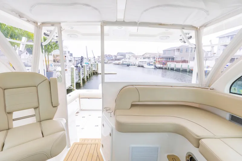 Slide: The Image of 2018 Pursuit OS 385 Offshore boat interior with beige seating and waterfront view. - 46