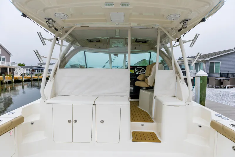 Slide: The Image of 2018 Pursuit OS 385 Offshore boat interior with seating and storage, docked near waterfront homes. - 6