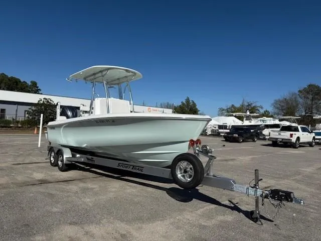 Slide: The Image of 2024 Contender 24 Sport boat on trailer in parking lot under clear blue sky. - 1