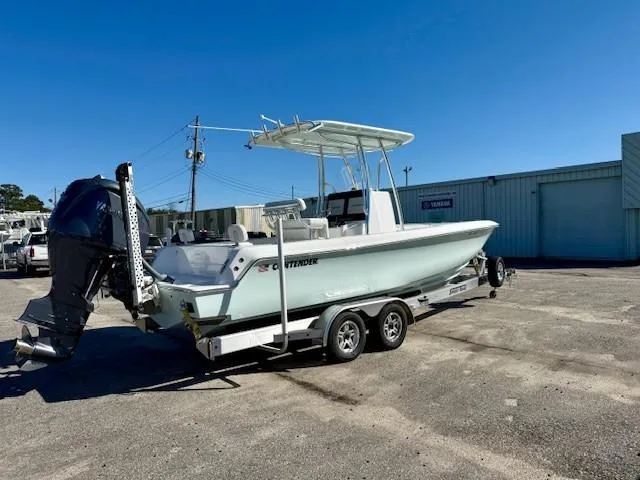 Slide: The Image of 2024 Contender 24 Sport boat on trailer, parked outdoors under clear blue sky. - 2