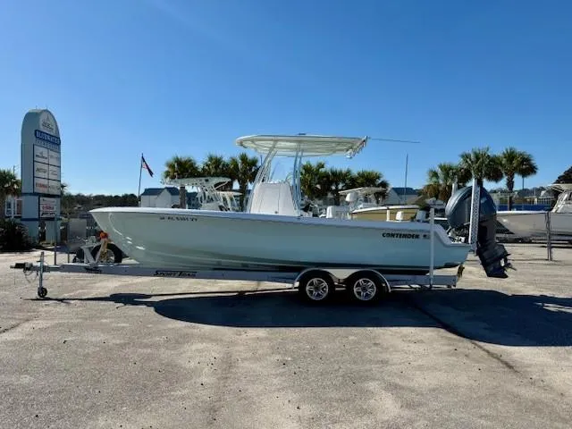 Slide: The Image of 2024 Contender 24 Sport boat on trailer, parked outdoors under clear blue sky. - 5