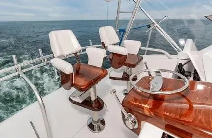 Slide: The Image of 2006 Viking 48 yacht helm with ocean view, featuring polished wood and white seating. - 7