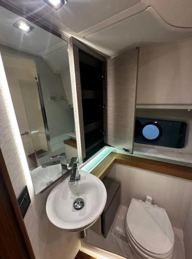 Slide: The Image of 2023 Tiara Yachts 43 LE bathroom with modern sink, mirror, and porthole window. - 16
