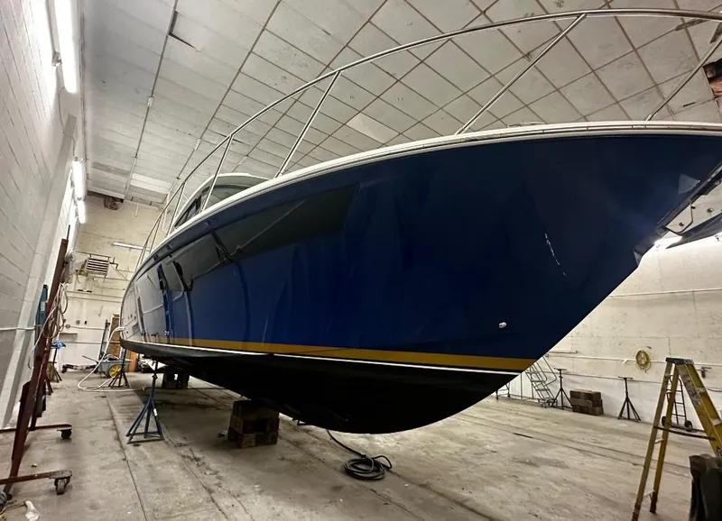 Slide: The Image of 2023 Tiara Yachts 43 LE in a workshop, showcasing sleek blue hull design. - 29