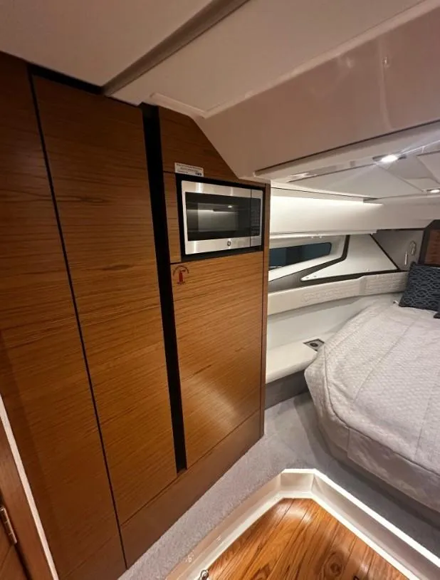 Slide: The Image of 2023 Tiara Yachts 43 LE interior cabin with modern wood finish and cozy bedding. - 7
