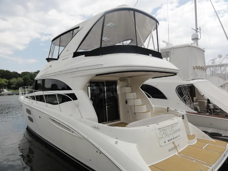 Slide: The Image of 2009 Meridian 441 Sedan yacht docked, featuring sleek design and spacious upper deck. - 2
