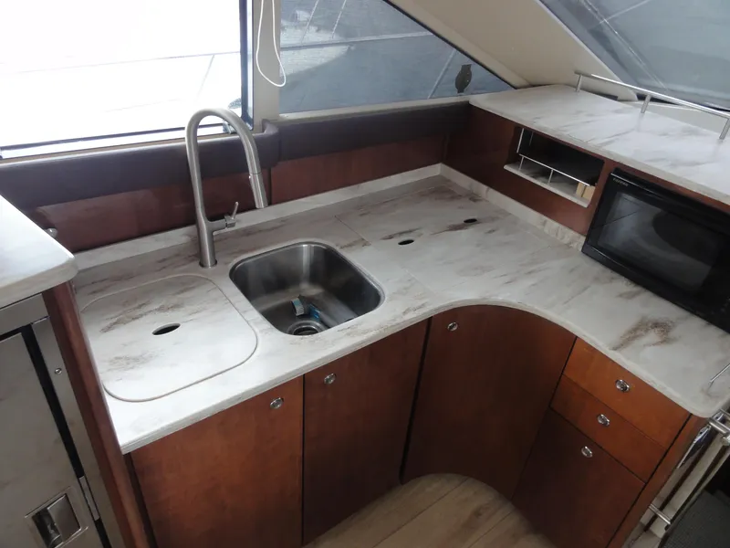 Slide: The Image of 2009 Meridian 441 Sedan yacht kitchen with sink, microwave, and wooden cabinetry. - 29