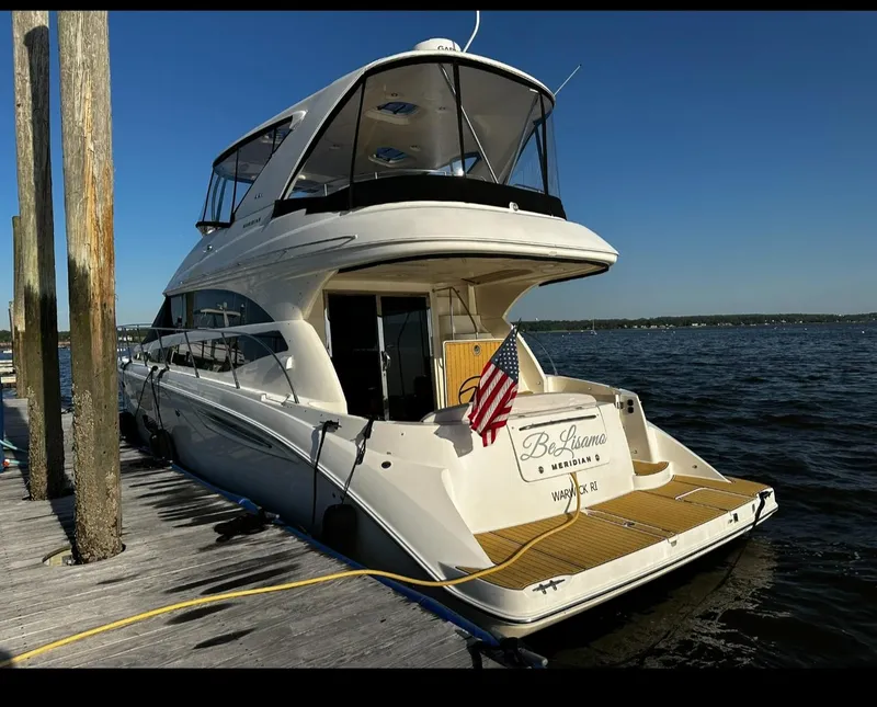 Slide: The Image of 2009 Meridian 441 Sedan yacht docked, rear view with American flag, clear blue sky. - 3
