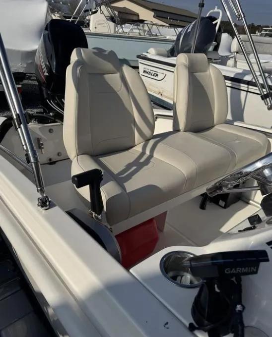 Slide: The Image of 2024 Boston Whaler 130 Super Sport boat interior with beige seating and Garmin equipment. - 23