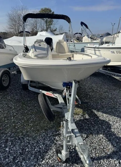 Slide: The Image of 2024 Boston Whaler 130 Super Sport boat on trailer, parked on gravel lot. - 25