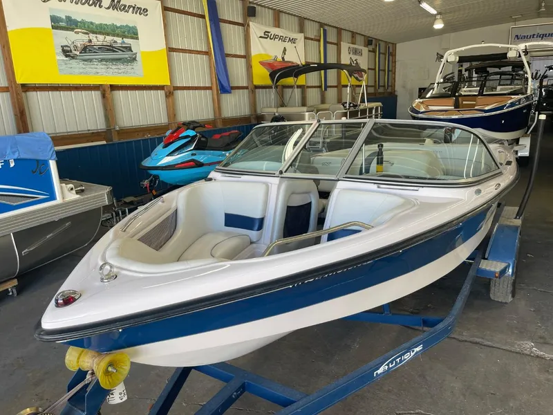 Slide: The Image of 2006 Nautique Ski 206 boat in showroom, blue and white design, on trailer. - 11