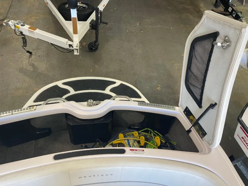 Slide: The Image of 2006 Nautique Ski 206 boat interior with open storage compartment and visible trailer. - 30