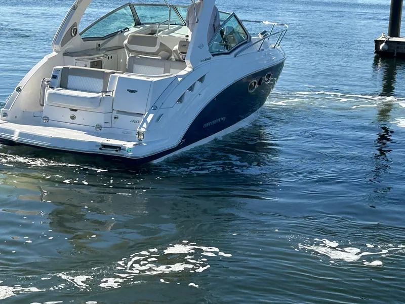 Slide: The Image of 2014 Chaparral 310 Signature boat on water, rear view, white and blue design. - 2
