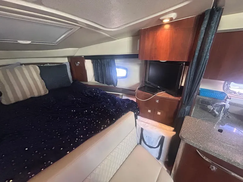 Slide: The Image of 2014 Chaparral 310 Signature cabin interior with bed, kitchenette, and wooden cabinetry. - 26