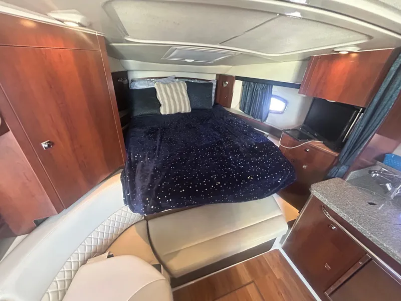 Slide: The Image of 2014 Chaparral 310 Signature cabin interior with bed, wood cabinets, and seating area. - 30