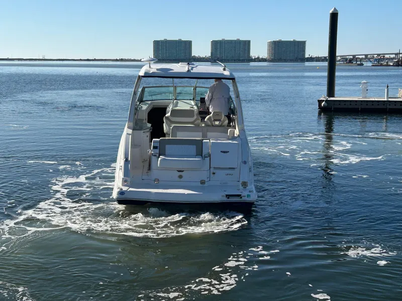 Slide: The Image of 2014 Chaparral 310 Signature boat navigating calm waters near a marina. - 4