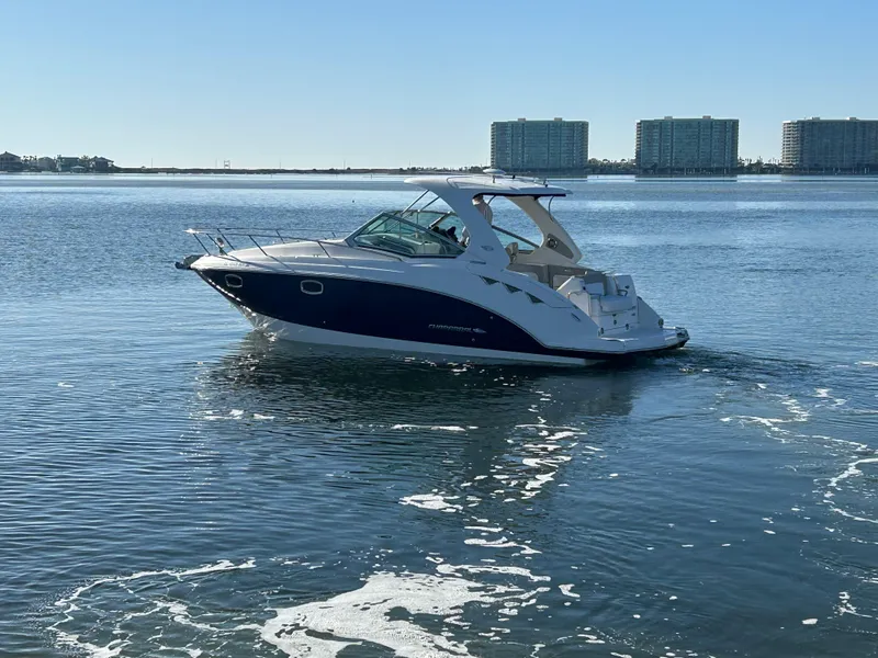 Slide: The Image of 2014 Chaparral 310 Signature boat cruising on calm waters with cityscape background. - 5