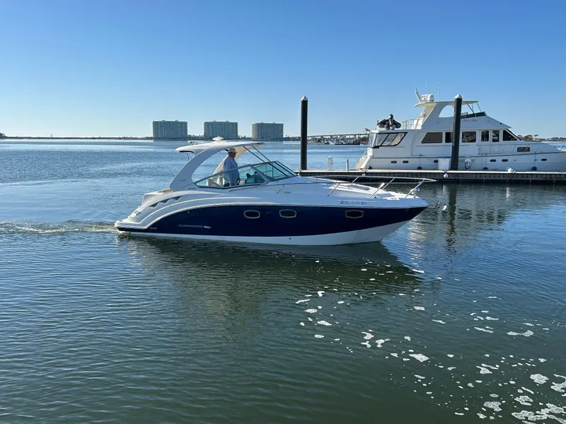 Slide: The Image of 2014 Chaparral 310 Signature Axis boat cruising on calm water near a marina. - 8