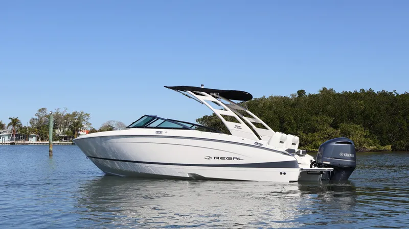 Slide: The Image of 2022 Regal LX4 boat on calm water with lush greenery in the background. - 1