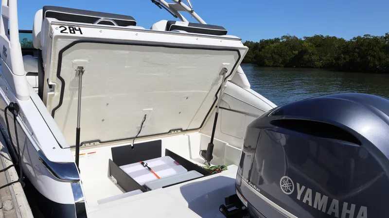 Slide: The Image of 2022 Regal LX4 boat with Yamaha engine, open storage compartment, docked by a scenic waterway. - 14