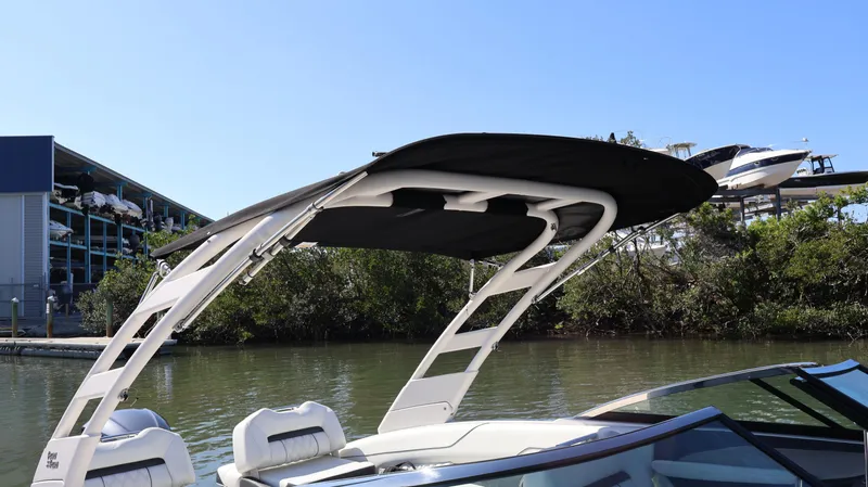 Slide: The Image of 2022 Regal LX4 boat with canopy on a calm river, surrounded by trees and a marina. - 39