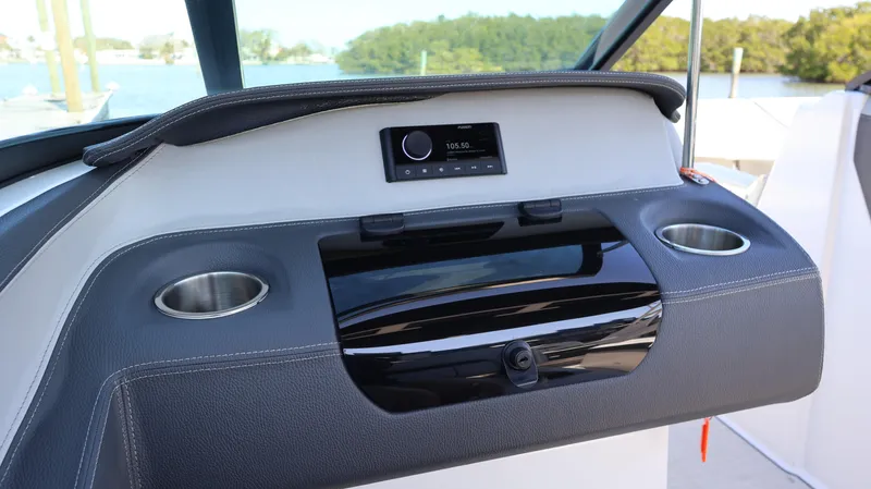 Slide: The Image of 2022 Regal LX4 boat dashboard with stereo system and cup holders, overlooking water. - 45