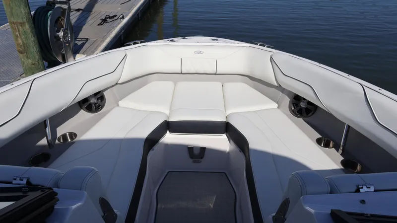 Slide: The Image of 2022 Regal LX4 boat interior with white seating and cup holders, docked by the water. - 46