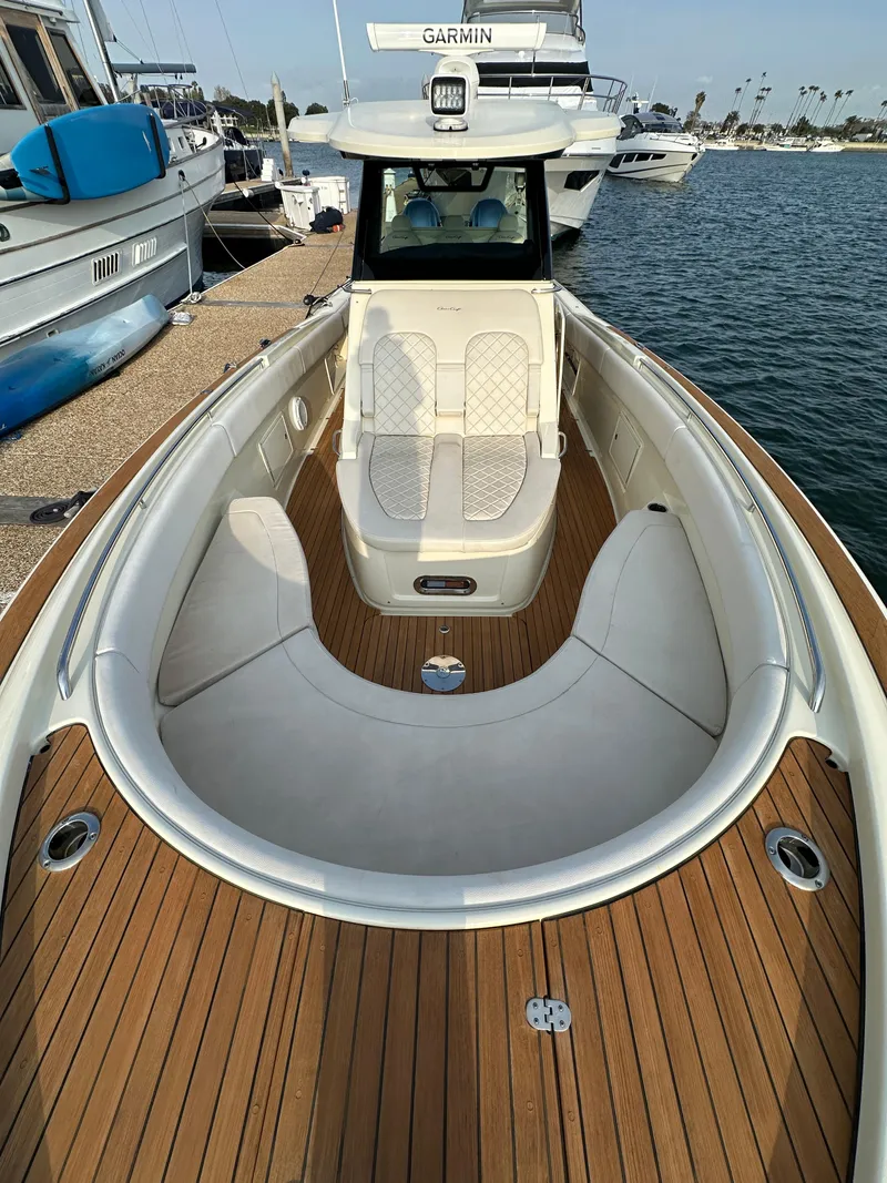 Slide: The Image of A 2021 Chris-Craft Catalina 34 docked. It features a sleek wooden deck and white upholstery. - 20