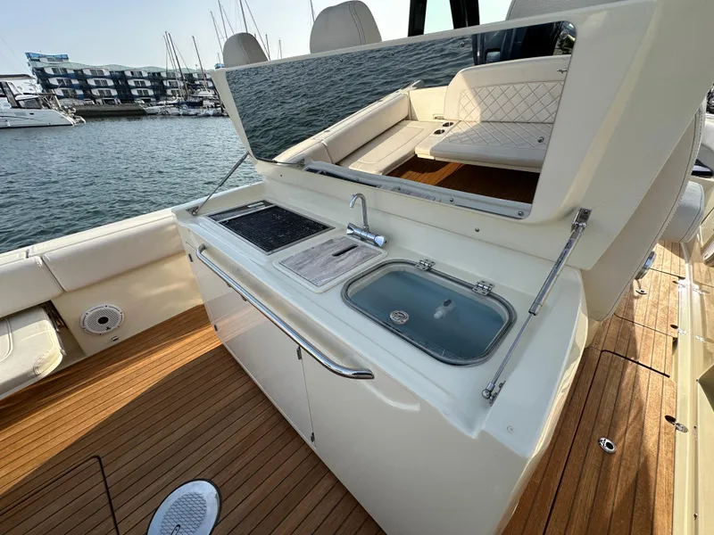 Slide: The Image of The 2021 Chris-Craft Catalina 34 features an outdoor kitchen with a sink and grill on a wooden deck. - 10