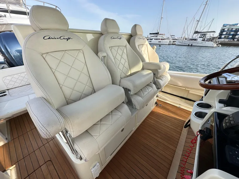 Slide: The Image of The 2021 Chris-Craft Catalina 34 features luxurious, quilted seats with armrests, set against a marina backdrop. - 11