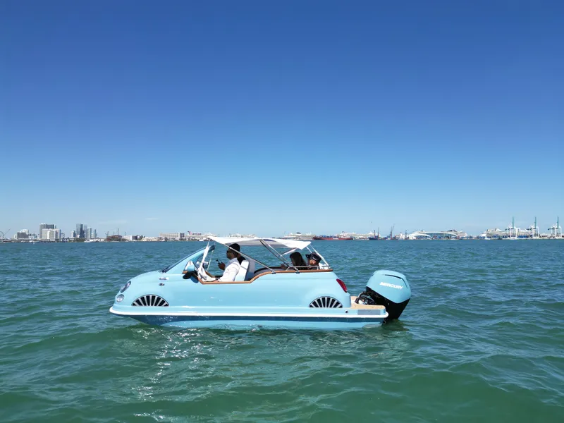 Slide: The Image of Amphibious Fiat 500 Classic boat on water, 2025 model, clear blue sky background. - 2