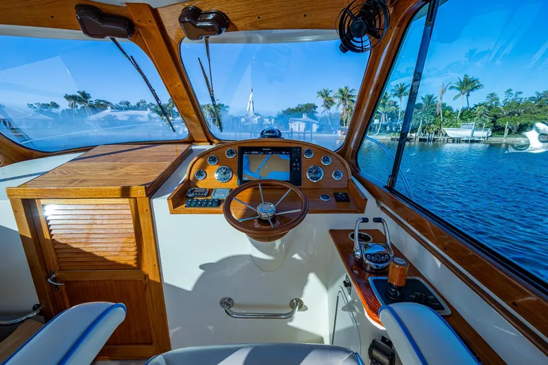 Slide: The Image of 2016 Hinckley Talaria 34 yacht cockpit with wooden dashboard and scenic water view. - 16