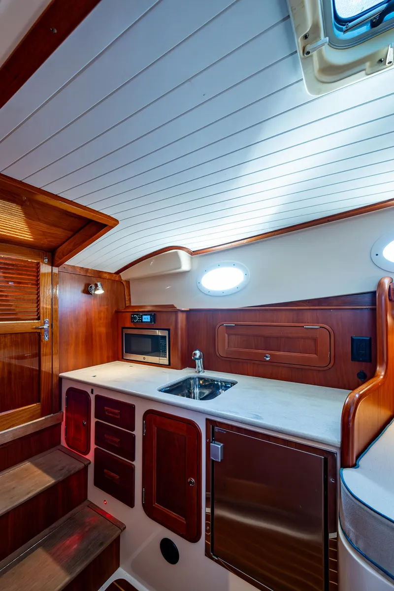 Slide: The Image of 2016 Hinckley Talaria 34 yacht interior with wooden cabinetry and compact kitchen area. - 18