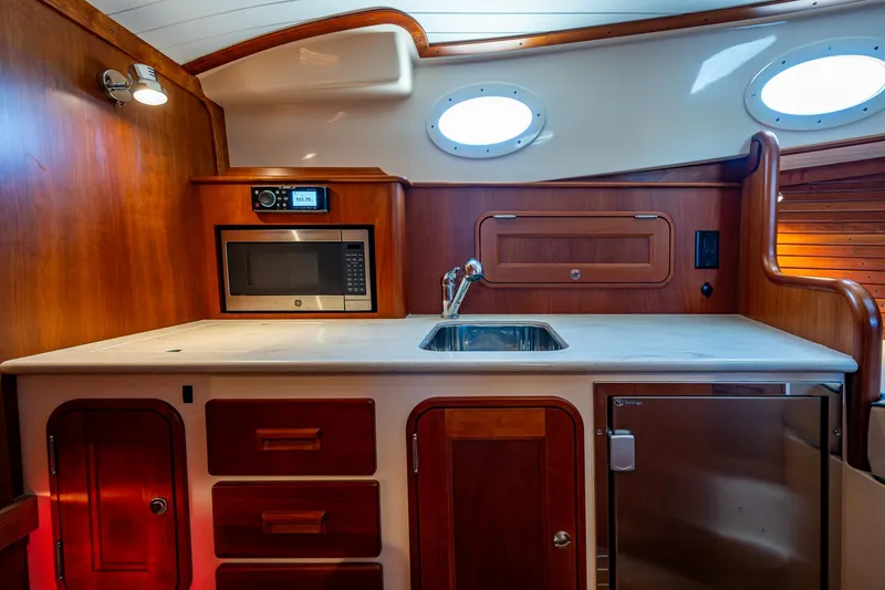 Slide: The Image of Interior of 2016 Hinckley Talaria 34 yacht kitchen with sink, microwave, and wooden cabinetry. - 19