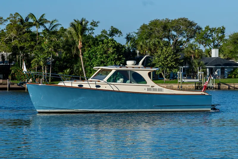 Slide: The Image of 2016 Hinckley Talaria 34 boat on calm water with lush greenery background. - 2