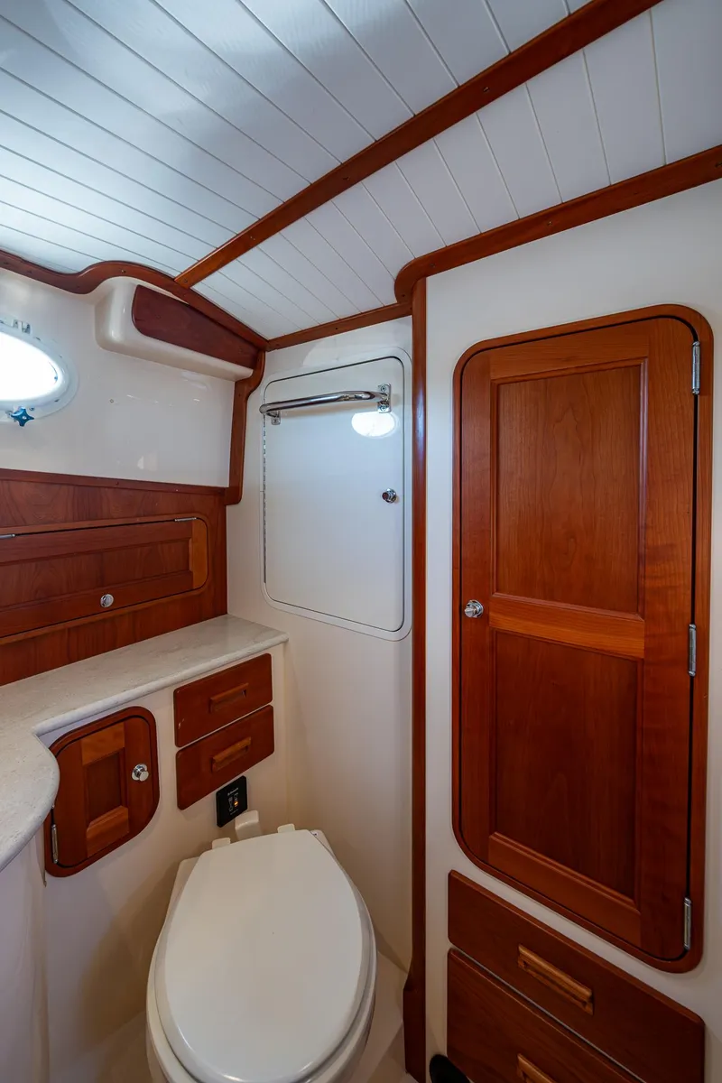 Slide: The Image of 2016 Hinckley Talaria 34 yacht bathroom with wooden cabinetry and white fixtures. - 24