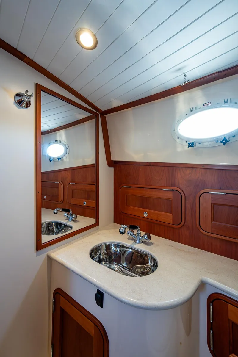 Slide: The Image of 2016 Hinckley Talaria 34 yacht bathroom with wooden accents and stainless steel sink. - 26